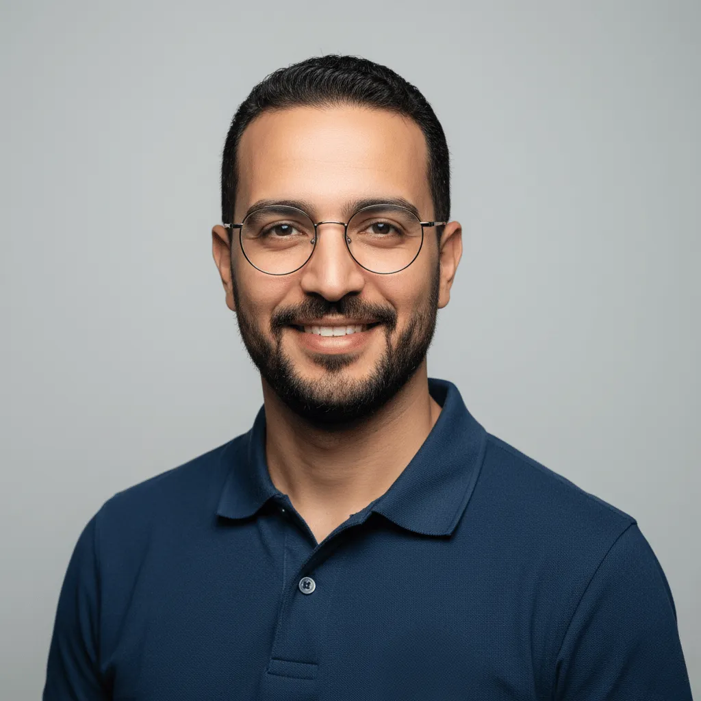 Portrait professionnel en studio de Brahim Amhal, le spécialiste de l'expérience utilisateur chez Visiona.ma. Il porte des lunettes et un polo bleu.