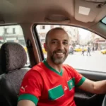 Youssef Benali, un client satisfait de Visiona.ma et passionné de football, souriant dans sa voiture au Maroc après avoir profité d'un match sans coupure.